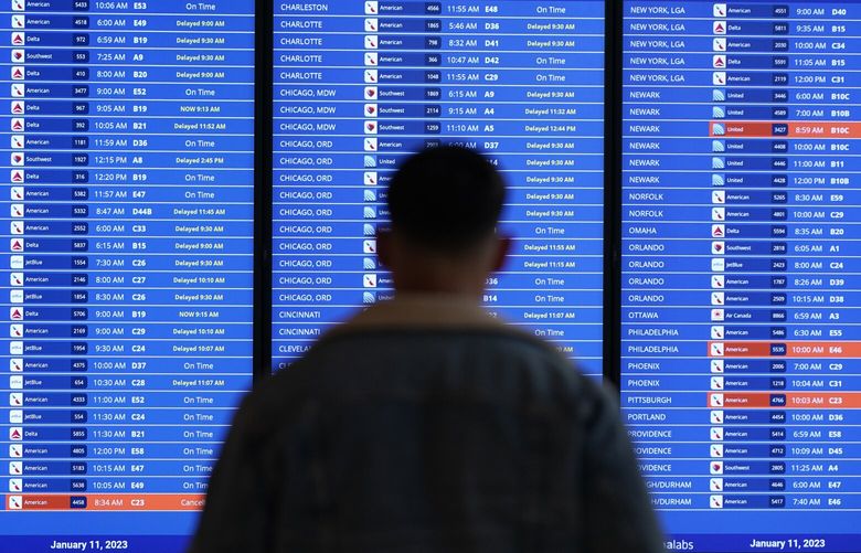 A traveler looks at a flight board with delays and cancellations at Ronald Reagan Washington National Airport in Arlington, Va., Wednesday, Jan. 11, 2023. Flights are being delayed at multiple locations across the United States after a computer outage at the Federal Aviation Administration. (AP Photo/Patrick Semansky) VAPS301 VAPS301