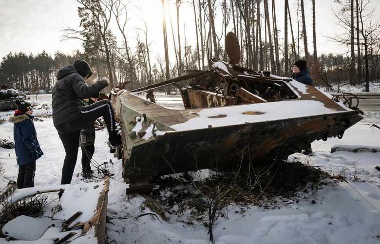 Youths from nearby Irpin kick a destroyed Russian military vehicle, now covered in snow in Dmytrivka, Ukraine on Wednesday, Jan. 11, 2023. Intense fighting continued in the eastern Ukrainian town of Soledar on Wednesday, despite a claim by the Wagner mercenary force that it had seized control of the town. (Lynsey Addario/The New York Times) – NO SALES – XNYT38 XNYT38