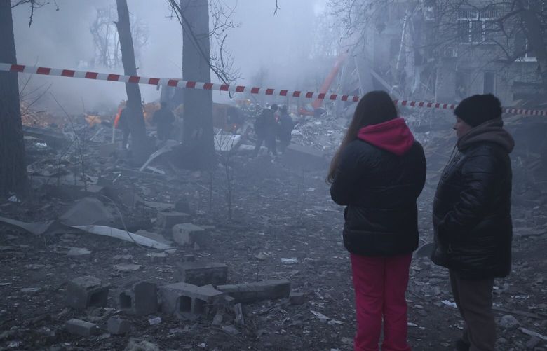 Local citizens look at Donetsk’s emergency employees working at a site of a shopping center destroyed after what Russian officials in Donetsk said it was a shelling by Ukrainian forces, in Donetsk, in Russian-controlled Donetsk region, eastern Ukraine, Monday, Jan. 16, 2023. (AP Photo/Alexei Alexandrov) XAZ117 XAZ117