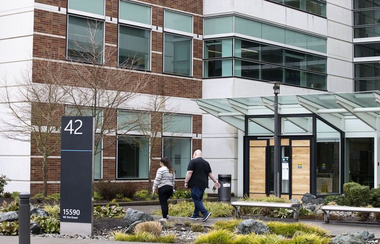 Employees walk into Microsoft Building 42 on the east campus in Redmond on Monday, Feb. 14, 2022. Microsoft announced Monday that it will reopen its Washington offices later this month.
