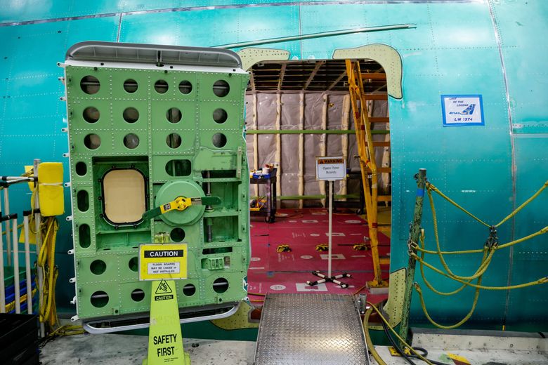 Signs at a passenger entry door alert employees to open floor boards during assembly. Within, stairs lead to the upper deck on the final 747. (Jennifer Buchanan / The Seattle Times)