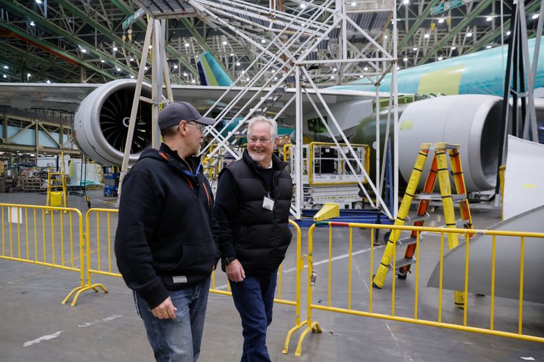 Vic Anderson, left, and his father, Kelvin, walk across the factory floor past the very last 747. Vic was the team lead on assembly of the 747 center fuselage and final body join, and his father is an “Incredible,” part of the crew that built the very first 747 in the late 1960s. (Jennifer Buchanan / The Seattle Times)