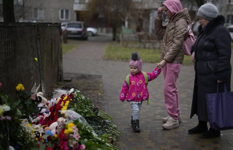 People pay their respects at the scene where a helicopter crashed into civil infrastructure on Wednesday, in Brovary, on the outskirts of Kyiv, Ukraine, Friday, Jan. 20, 2023. (AP Photo/Daniel Cole) DCO111 DCO111
