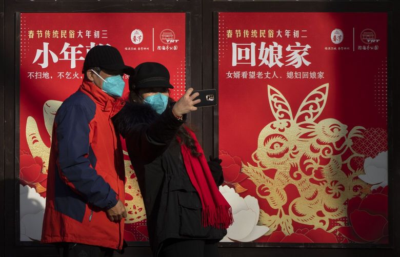 Visitors wearing face masks pose in front of a row of Year of the Rabbit themed billboards at a public park in Beijing on the first day of the Lunar New Year holiday, Sunday, Jan. 22, 2023. (AP Photo/Mark Schiefelbein) XMAS102 XMAS102