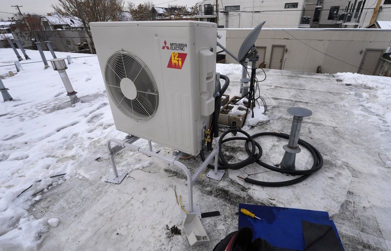 A condenser sits on the roof during the installation of a heat pump in an 80-year-old rowhouse Friday, Jan. 20, 2023, in northwest Denver. (AP Photo/David Zalubowski)