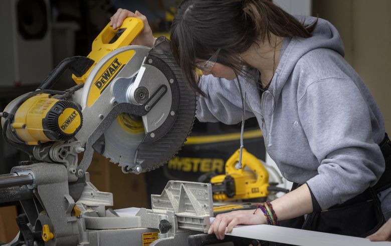 Ellie Fongemie of Camano Island makes a last check before cutting a piece of trim that will be attached to the tiny home that she is building with other students at the Advanced Manufacturing Skills Center event at Paine Field in Everett. (Ellen M. Banner / The Seattle Times)