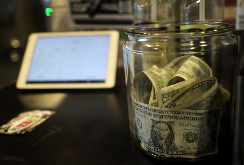 A tip jar sits on the counter of City Grind Espresso at Seattle’s City Hall. (Greg Gilbert / The Seattle Times)