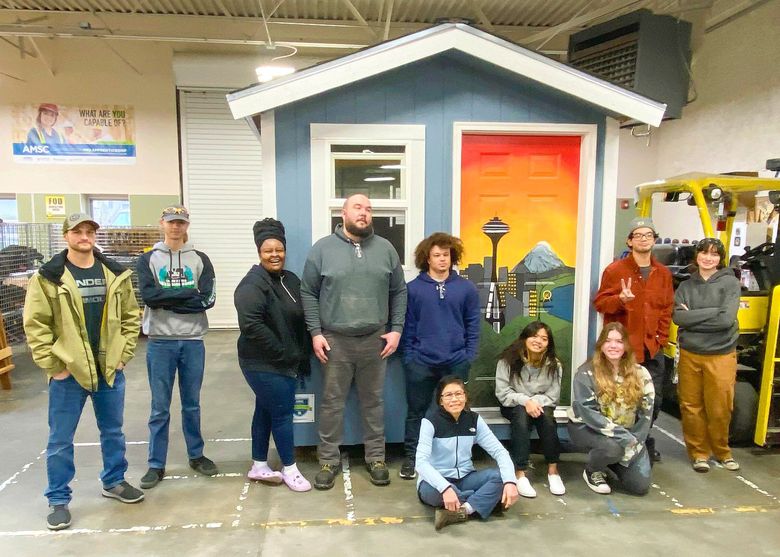 The nine students at a recently completed free, 10-week Construction Pre-Apprenticeship program run by Edmonds College, built a tiny house that’ll be given to a village for unsheltered people. In the middle is Brad Farnum, their instructor. (Courtesy Edmonds College)