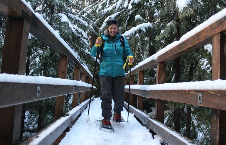 Wallingford resident Lisa Harris crosses a footbridge over Humpback Creek on a snowshoe outing from the new Annette Lake Sno-Park.