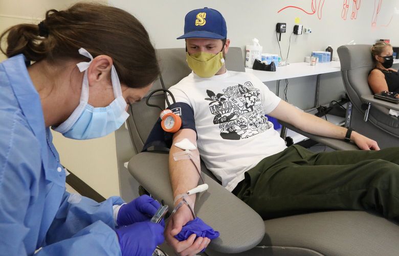 Phlebotomist Ann Marie Ogle, left, unhooks a tube from Taylor Knowles of W. Seattle, who is done donating blood at Bloodworks Northwest, Monday, June 21, 2021 in Seattle. The region’s hospitals and trauma centers are experiencing a critical shortage in blood supply as donors have dropped off and more hospital operations resume. 217456