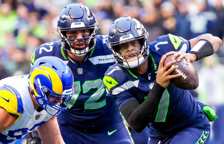 Seattle Seahawks quarterback Geno Smith scrambles away from Los Angeles Rams defensive tackle Michael Hoecht, left, and defensive tackle Marquise Copeland for a nine yard gain during the fourth quarter. 222737 222737