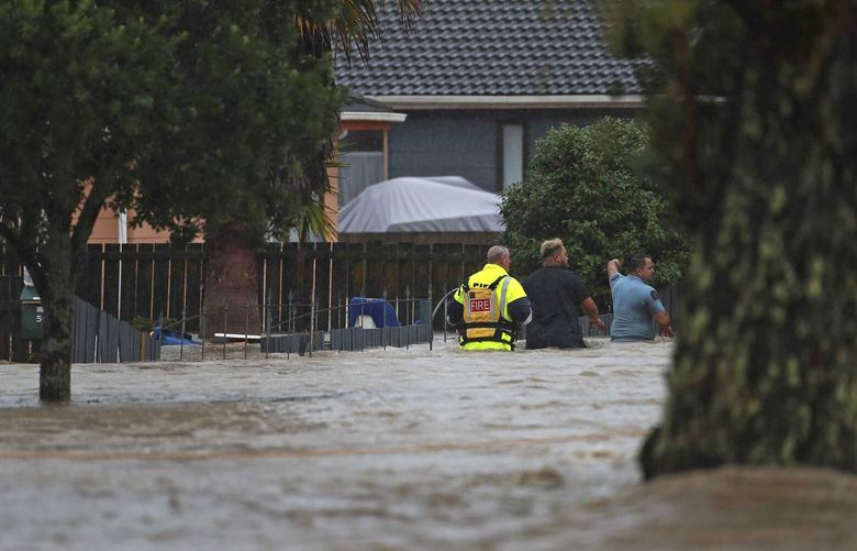 Emergency workers and a man wade through flood waters in Auckland, New Zealand, Friday, Jan. 27, 2023. Torrential rain and wild weather in Auckland causes disruptions throughout the city and an Elton John concert to be canceled just before it was due to start. (Hayden Woodward/New Zealand Herald via AP) XNZH803 XNZH803