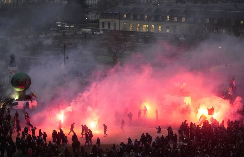 Protestors walk through flares smoke at the end of the demonstration against plans to push back France’s retirement age, Tuesday, Jan. 31, 2023 in Paris. Labor unions aimed to mobilize more than 1 million demonstrators in what one veteran left-wing leader described as a “citizens’ insurrection.” The nationwide strikes and protests were a crucial test both for President Emmanuel Macron’s government and its opponents. (AP Photo/Thibault Camus) PAR173 PAR173