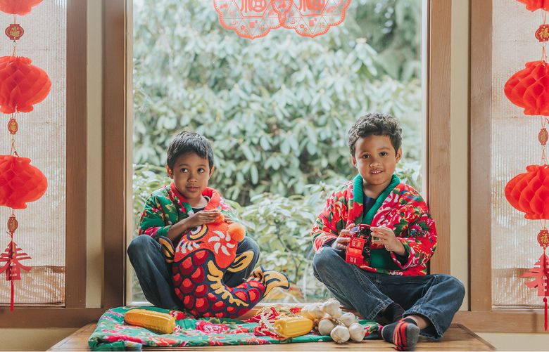 Cynthia Yu’s sons, Alex Hampton, 6, and Daniel Hampton, 8, of Maple Valley, with Lunar New Year decorations. The character in the cut paper on the window says fu, which means blessing. Red is the color for good luck, and the fish symbolizes abundance. (Courtesy Cynthia Yu)

