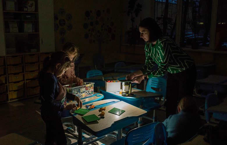 A teacher gives a lesson using flashlights during a blackout at a public school in Kyiv, Ukraine, on Dec. 21, 2022. In Kyiv, Russian strikes and power outages are part of the school day, but teachers and students press on with resolve. (Laura Boushnak/The New York Times)