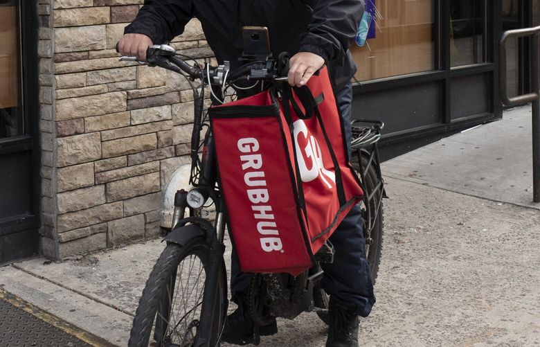 A delivery man bikes with a food bag from Grubhub, Wednesday, April 21, 2021 in New York. (AP Photo/Mark Lennihan)