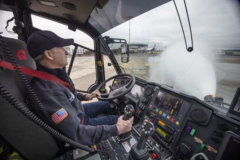 Jay Williams, a driver/engineer with the Port of Seattle Fire Department, sprays water from an aircraft rescue firefighting vehicle at Sea-Tac Airport. During a fire, the vehicle pumps out 600-1,200 gallons a minute, mixing water with firefighting foam concentrate stored on board. (Ellen M. Banner / The Seattle Times)