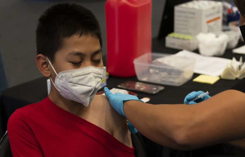 FILE – Johnny Thai, 11, receives the Pfizer COVID-19 vaccine at a pediatric vaccine clinic for children ages 5 to 11 set up at Willard Intermediate School in Santa Ana, Calif., Nov. 9, 2021. On Friday, Feb. 3, 2023, the California Department of Public Health said it was no longer exploring emergency rules to add the COVID-19 vaccine to the list of required school vaccinations. (AP Photo/Jae C. Hong,File) LA518 LA518