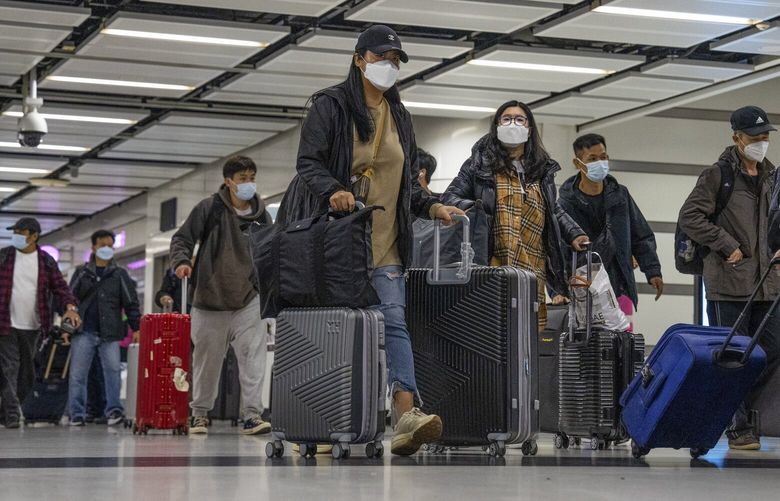 FILE – Travelers wearing face masks with their luggage head to the immigration counter at the departure hall at Lok Ma Chau station following the reopening of crossing border with mainland China, in Hong Kong, Sunday, Jan. 8, 2023. Hong Kong authorities announced Friday, Feb. 3, 2023, that they will lift a quota on the number of cross-border travelers with China and scrap mandatory COVID-19 PCR testing requirements as both places seek to drive economic growth. (AP Photo/Bertha Wang, File) XHKG102 XHKG102