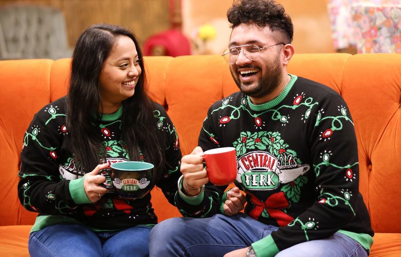 Shreya and Heerak Thakar from Seattle who are engaged to be married pose with coffee cups while wearing Central Perk sweaters on an orange couch simulating the coffee shop from the show. The Friends show was one of the first things they bonded on when they first met as students at University of Michigan. They bought the sweaters two years ago but have never worn them until today. They came to the exhibit to celebrate Heerak’s birthday. Fans check out the new interactive exhibit at Pacific Place, The FRIENDS Experience: The One in Seattle at Pacific Place on Wednesday, February 1, 2023. The exhibit features re-creations of the “Friends” set and runs from Feb.1 to April 30.