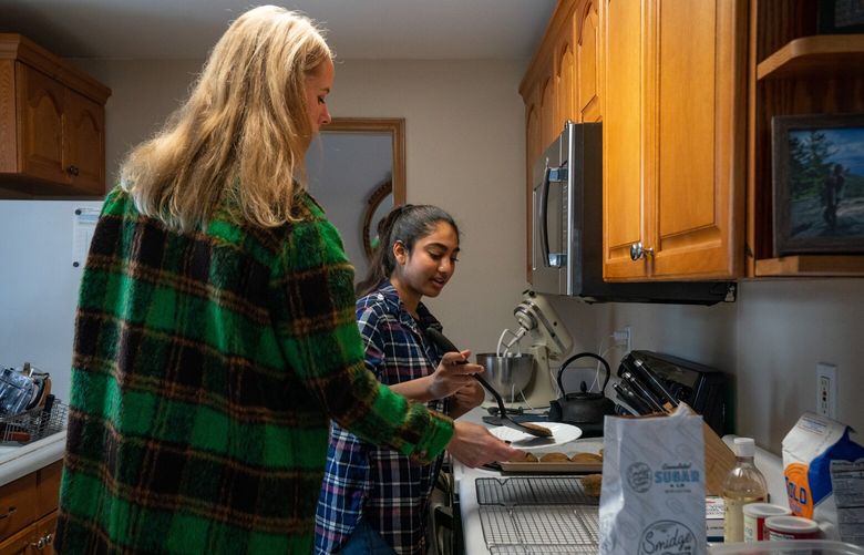 Tara Kankesh, right, serves a freshly baked ginger molasses cookie onto a plate her mentor, Lindsey Greenlee, holds out on Sunday, Dec. 4, 2022. The two have been matched through Big Sister, Little Sister since December 2019.