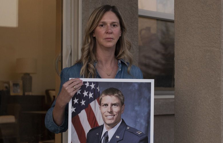 Jenny Holmes poses with a photo of her husband, Mark Holmes, at her home in Colorado Springs on Thursday. Mark Holmes, a former missileer, died in 2020 from non-Hodgkin’s Lymphoma. MUST CREDIT: Photo for The Washington Post by Rachel Woolf