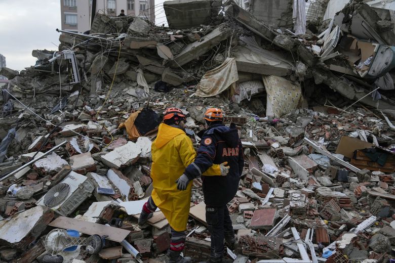 Emergency team members pause for a moment as they search for people in a destroyed building in Adana, Turkey, on Monday. A powerful quake knocked down multiple buildings in southeast Turkey and Syria. (Khalil Hamra / AP)