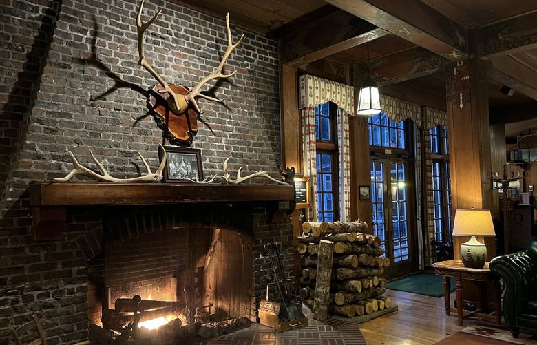 A wood-burning fireplace is the centerpiece of a cozy lobby inside Lake Quinault Lodge. Comfortable furniture and soft lighting invite lingering on rainy days.