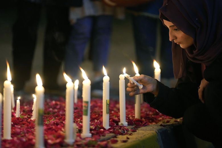 A woman lights candles during a vigil in Islamabad, Pakistan, for victims of the earthquake in Syria and Turkey. (Anjum Naveed / The Associated Press)