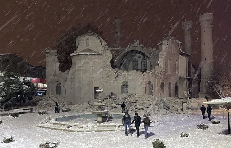 People walk next to a mosque destroyed by an earthquake in Malatya, Turkey, Monday, Feb. 6, 2023. A powerful quake has knocked down multiple buildings in southeast Turkey and Syria and many casualties are feared. (DIA images via AP) FS101 FS101
