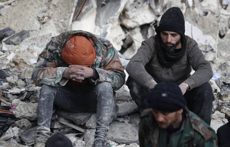 People react as they sit on the wreckage of collapsed buildings, in Aleppo, Syria, Tuesday, Feb. 7, 2023. Rescuers raced Tuesday to find survivors in the rubble of thousands of buildings brought down by powerful earthquake and multiple aftershocks that struck eastern Turkey and neighboring Syria. (AP Photo/Omar Sanadiki) HAS126 HAS126