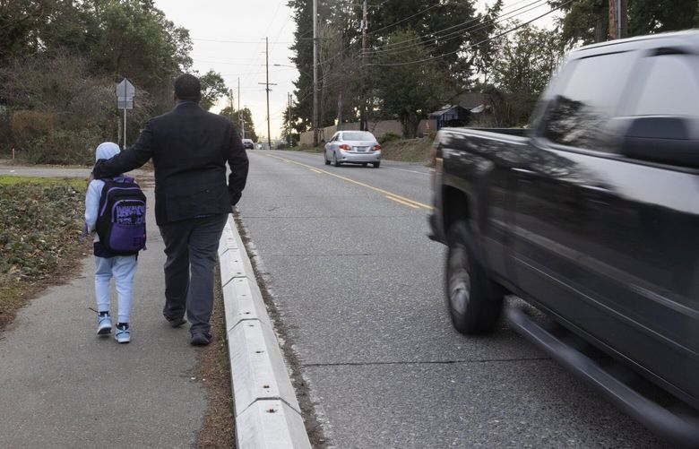 Joe Vinson walks home with his fourth grade son, Quentin, 9, on the way home from River Ridge Elementary School along Military Rd. S. in SeaTac Tuesday, January 31, 2023.  The school is in the Kent school district, although it is located in SeaTac.
  
 New apartments have opened  in a busy, lower income neighborhood, without new walkways for kids. A lapse by drivers on the fast roadway could kill. Unlike the politically potent safe streets movement in Seattle and certain other towns, this neglected part of Kent like much of the US still treats walk safety as an afterthought, in one of the area’s few affordable communities for families.


 222901
