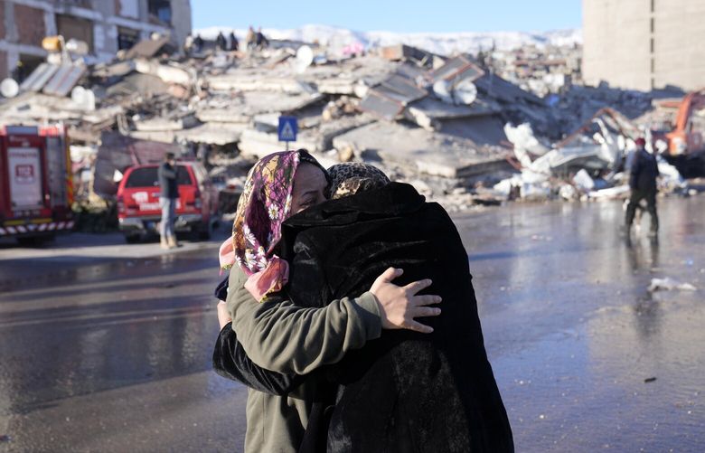 Two women hug each other in front of a destroyed building in Kahramanmaras, southern Turkey, Wednesday, Feb. 8, 2023. With the hope of finding survivors fading, stretched rescue teams in Turkey and Syria searched Wednesday for signs of life in the rubble of thousands of buildings toppled by a catastrophic earthquake. (AP Photo/Hussein Malla) XTS159 XTS159