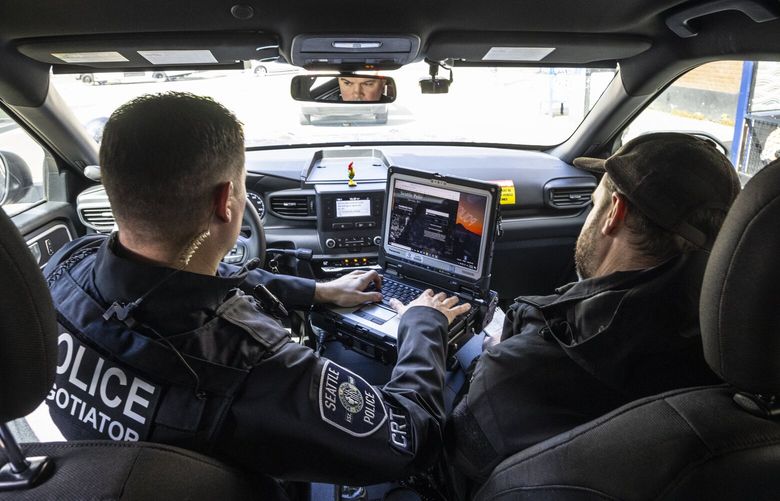 Tuesday, April 19, 2022.    Seattle Police Crisis Response Team members Collin Jevmore at right, a Mental Health Professional and Officer Joe Binder lookup a citizens mental health records before meeting with backup officers to check the man who was calling 911 repeatedly in distress.    220166