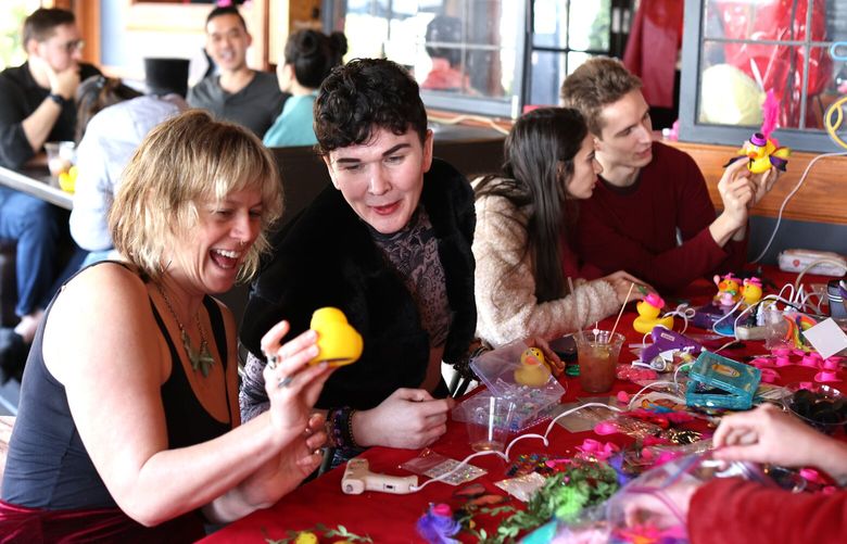 Fern Schultz, left, from Olympia shows Bryan Keleman a duck she is decorating at the Decoration Station. Duck Brunch held “My Ducky Valentine” at the Eastlake Bar and Grill in Seattle on Saturday, February 11, 2023. Duck Brunch is a pop-up party held monthly, always at different venues, always with a different theme, and always featuring rubber ducks.