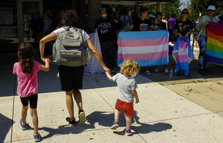 Parents with their children walk past supporters of the Drag Queen Story Hour in Maryland in July.