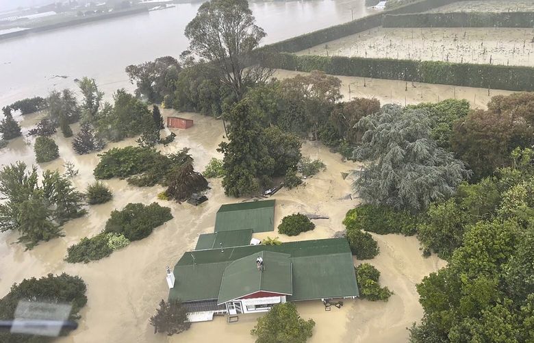 In this image released by the New Zealand Defense Force on Wednesday, Feb. 15, 2023, people stand on a rooftop of a home waiting to be winched to safety by helicopter in the Esk Valley, near Napier, New Zealand. The New Zealand government declared a national state of emergency Tuesday after Cyclone Gabrielle battered the country’s north in what officials described as the nation’s most severe weather event in years. (New Zealand Defense Force via AP) SYD102 SYD102