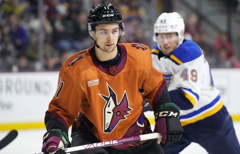 Arizona Coyotes right wing Dylan Guenther (11) and St. Louis Blues center Ivan Barbashev (49) watch the puck during the second period of an NHL hockey game in Tempe, Ariz., Thursday, Jan. 26, 2023. (AP Photo/Ross D. Franklin)