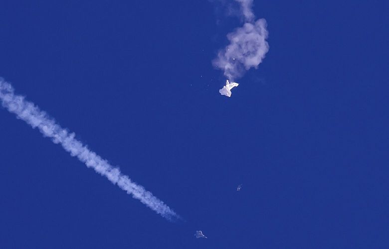 In this photo provided by Chad Fish, the remnants of a large balloon drift above the Atlantic Ocean, just off the coast of South Carolina, with a fighter jet and its contrail seen below it, Feb. 4, 2023. China said Tuesday, Feb. 7, 2023, it will “resolutely safeguard its legitimate rights and interests” over the shooting down of a suspected Chinese spy balloon by the United States, as relations between the two countries deteriorate further. (Chad Fish via AP, File) BKWS304 BKWS304