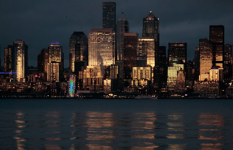 The Seattle Skyline is photographed during sunset in West Seattle Tuesday, Nov. 22, 2022. Drivers and pedestrians stopped to take photos of the shaft of light that illuminated the Seattle skyline against moody skies. 
 222268
