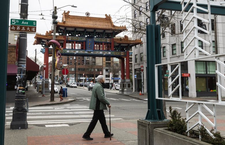 A man walks past the Historic Chinatown Gate, which is as stone’s throw to Sound Transit’s latest 4th Avenue S. hub concept, for 2037, that would be a mere 45 feet deep and between Union Station and King Street Station, Thursday, Feb. 16, 2023 in Seattle.
