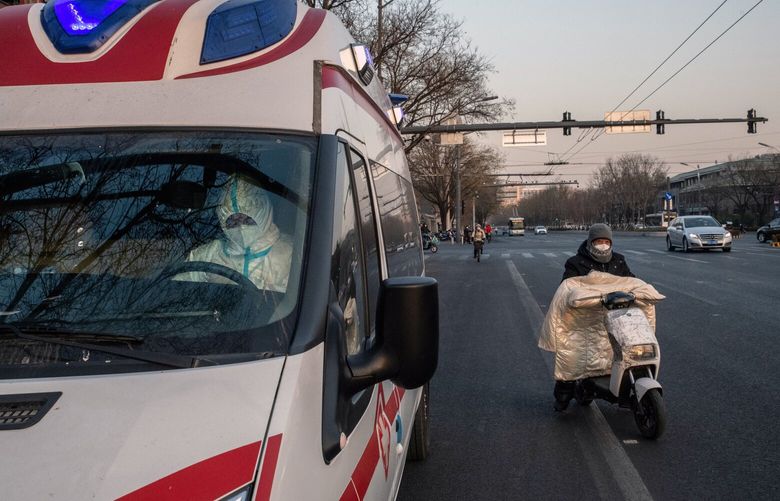 FILE – An ambulance driver in a protective suit parked at the side of a road in Beijing on Dec. 20, 2022. The two main types of insurance in China are employee hospitalization insurance and residents insurance. (Gilles Sabrie/The New York Times)