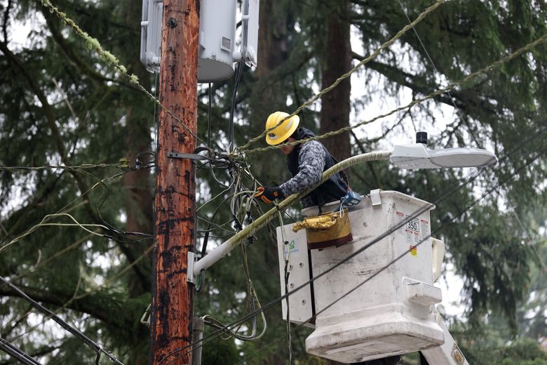 A utility lineman from Seattle City Light works to restore electricity after a November 2022 snowstorm caused widespread power outages in Lake Forest Park. (Karen Ducey / The Seattle Times)