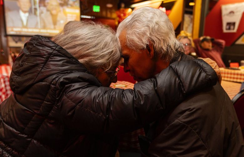 Fellow Seattle restaurant owner Voula Vlahos, left, who owns Voula’s Offshore Cafe next door, hugs Abdoullah Abdoullah, at a going-away party as Abdoullah’s Northlake Tavern closes for good, Tuesday, Jan. 31, 2023, in Seattle.