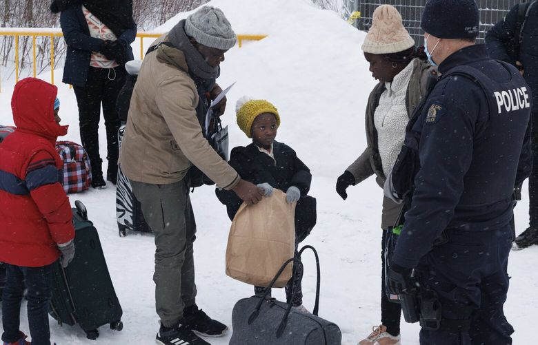 An Angolan family explaining to their young daughter that she can eat once she’s let inside the processing facility at the Roxham Road border crossing in Saint-Bernard-de-Lacolle, Quebec, Canada on Feb. 24, 2023. A post-pandemic surge in illegal crossings from the United States has led to calls to shut down the rural road on the border. (Nasuna Stuart-Ulin/The New York Times) XNYT13 XNYT13