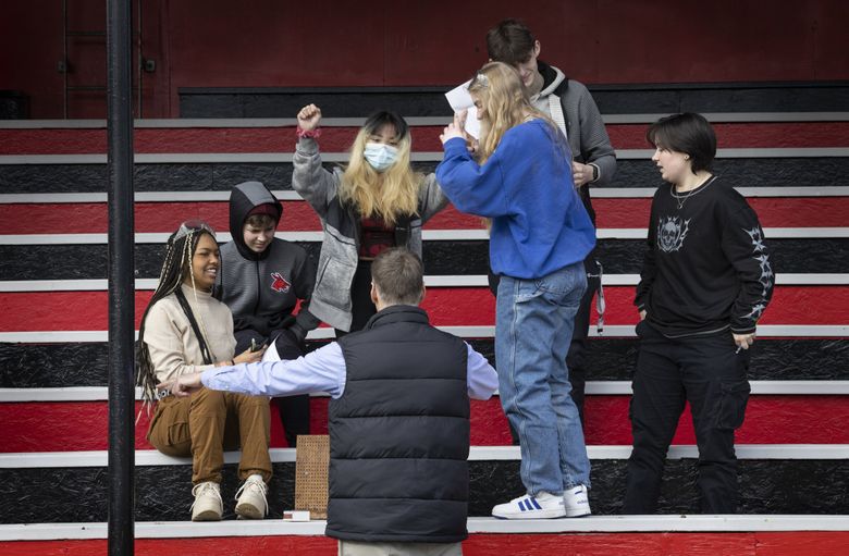 Science teacher Jeff Rooklidge celebrates with students after success on their experiment. They are doing the experiments outside on the bleachers because the classroom lacks proper ventilation. (Ellen M. Banner / The Seattle Times)