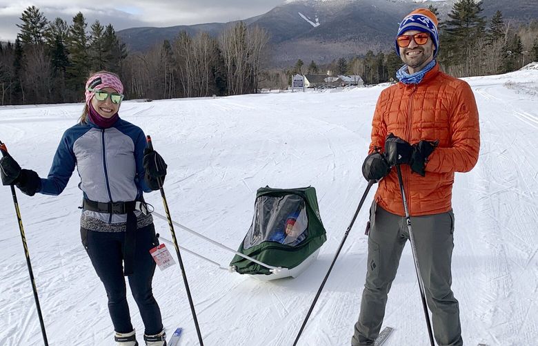 In this photo provided by Nancy Mazonson, Leah Ofsevit, left, and her husband, Jeremy Garczynski, pull their son Lewis Garczynski, in a sled at Waterville Valley Resort, in Waterville Valley, N.H., in January 2022. The New Hampshire resort is about two hours from their home, in Melrose, Mass. The family has lamented the fact that there has been very little snow this winter in the Boston area for them to go sledding and cross country skiing near their home. (Nancy Mazonson via AP) BX610 BX610