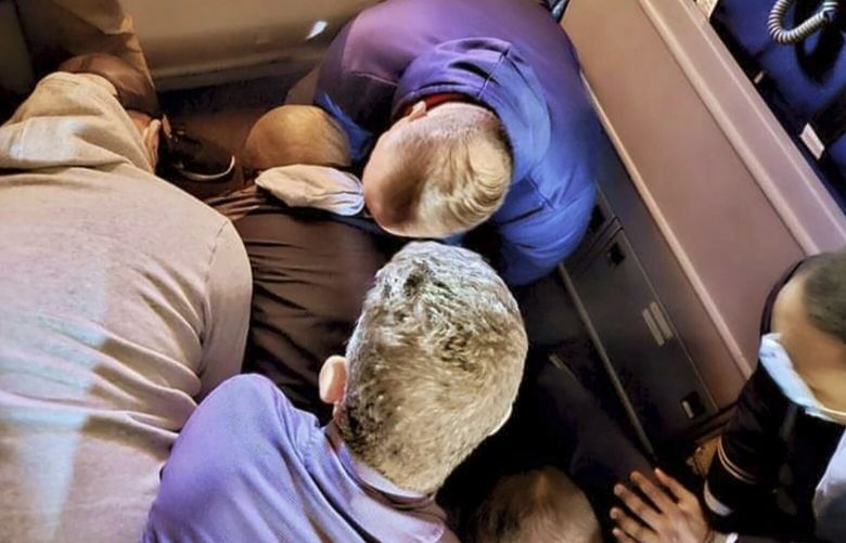 This image provided by Simik Ghookasian shows passengers and crew members restraining a man who according to federal authorities tried to open an airliner’s emergency door and tried to stab a flight attendant on a weekend flight from Los Angeles to Boston on Sunday, March 5, 2023. Simik Ghookasian, a passenger, said in a telephone interview that he was seated several rows behind the suspect, identified by federal authorities as Francisco Severo Torres, when he heard a commotion. (Simik Ghookasian via AP) MAHO101M MAHO101M