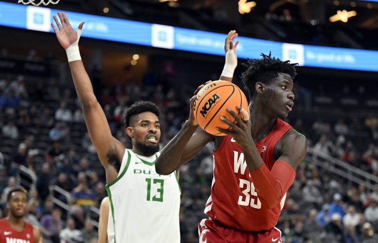 Washington State forward Mouhamed Gueye (35) looks to pass as Oregon forward Quincy Guerrier (13) defends during the second half of an NCAA college basketball game in the quarterfinals of the Pac-12 Tournament, Thursday, March 9, 2023, in Las Vegas. (AP Photo/David Becker)