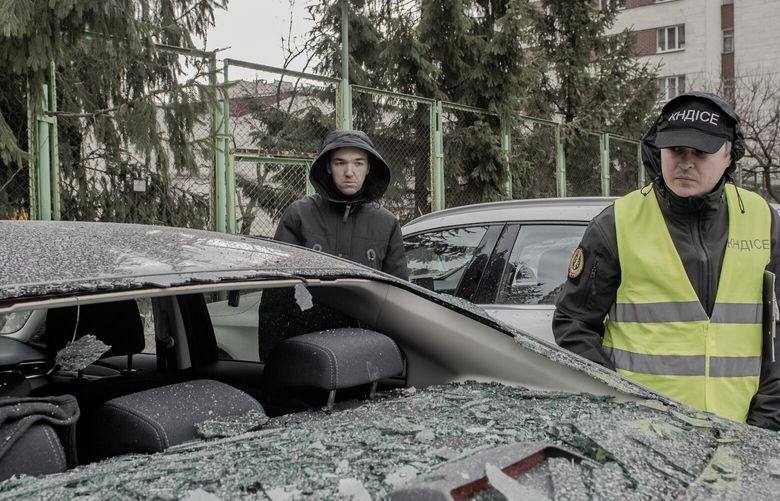 Maksym Pankratiev inspects his damaged car with a police officer at the scene where missile parts fell onto a residential parking lot and destroyed several cars in the Sviatoshynskyi district of Kyiv, March 9, 2023. Moscow fired an array of weapons, including hypersonic missiles, in its broadest attack on Ukraine in weeks. At least nine people were killed and power was knocked out in multiple regions. (Laetitia Vancon/The New York Times) XNYT112 XNYT112